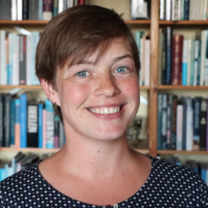 Foto af Ea foran en bogreol. Smilende kvinde i 30'erne med kort hår