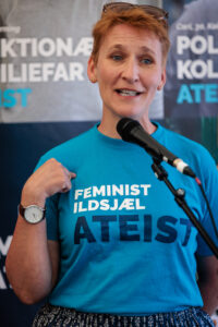 Sidse Haandbæk, bestyrelsesmedlem i Ateistisk Selskab, foran mikrofonen på Folkemødet 2025 i sin feminist, ildsjæl, ateist t-shirt