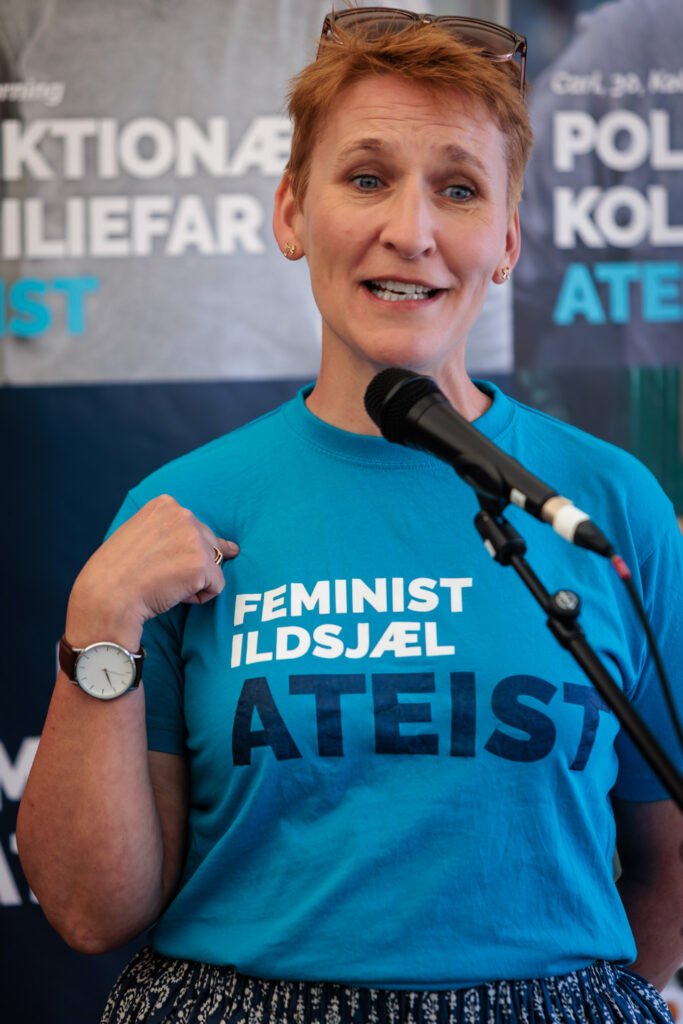 Sidse Haandbæk, bestyrelsesmedlem i Ateistisk Selskab, foran mikrofonen på Folkemødet 2025 i sin feminist, ildsjæl, ateist t-shirt